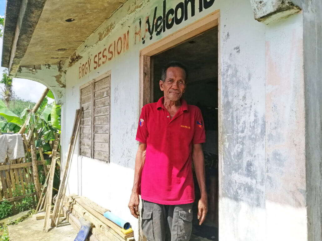 Tatay Carlos stands outside what used to be the barangay hall of Brgy. Guinsaanan and is now his temporary home after Typhoon Rolly destroyed his house